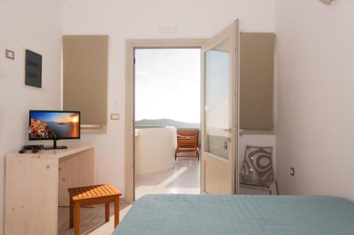 a bedroom with a bed and a tv and a window at Caldera's Majesty in Imerovigli
