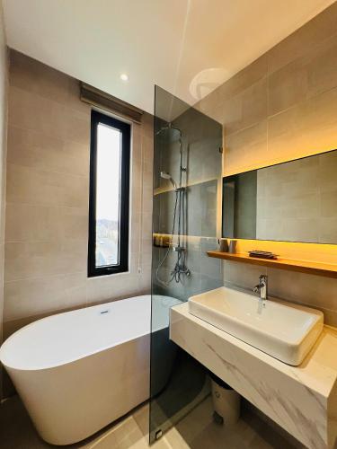 a bathroom with a white tub and a sink at Cozy Garden Boutique hotel in Khu Chi Lăng