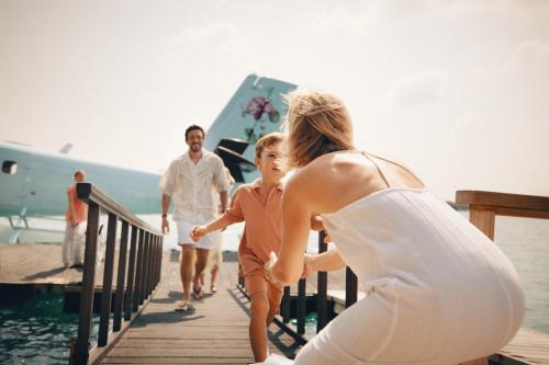 a woman and a man walking down a dock with a child at JOALI Maldives in Raa Atoll
