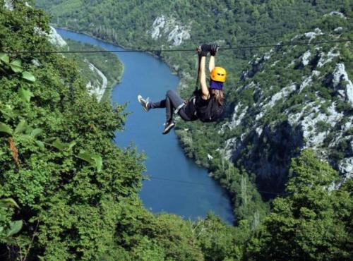 a person hanging on a zip line over a river at Apartmani Villa Borzic in Omiš