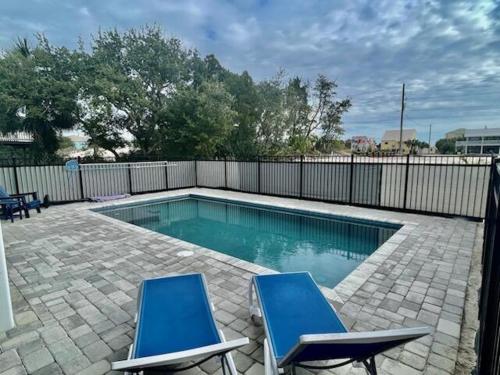 two blue chairs and a swimming pool in a backyard at Fruitcakes- Private Pool- Hot Tub- Pet Friendly in St. George Island
