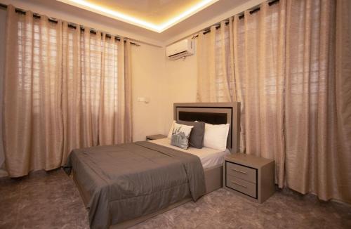 - une chambre avec un lit dans une chambre avec des rideaux dans l'établissement Agape Villa, à Sékondi