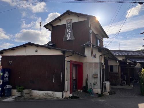 a brown and white house with a red door at いけだ屋 in Kōzai