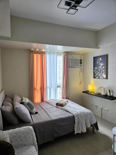 a bedroom with a large bed with a window at Pool view Studio with WiFi & Netflix , Avida Riala in Cebu City