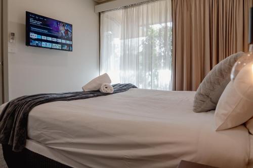 a bedroom with a large white bed with a window at Mitchell On Main in Bairnsdale