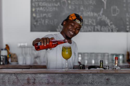 a man pouring a drink into a wine glass at The Loop Beach Resort in Jambiani