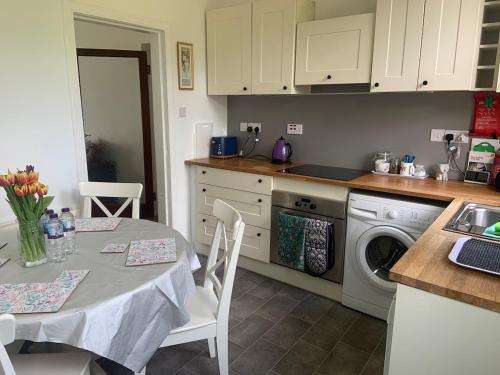 a kitchen with a table and a sink and a dishwasher at Holiday Home with free parking & 4min to Edinburgh Warverly in Fisherrow