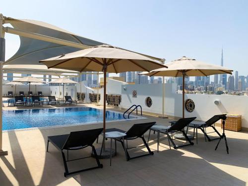 a patio with tables and umbrellas and a pool at Al Khoory Executive Hotel, Al Wasl in Dubai