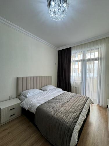 a bedroom with a large bed and a chandelier at Paradise- 2 rooms in Sumqayyt