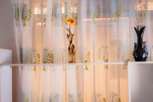 a curtain with two vases and flowers on a shelf at Kivu Greenstars Apartment in Gisenyi