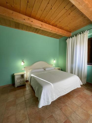 a bedroom with a white bed and a wooden ceiling at Le Calvie, country house in Camerino