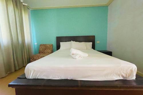 a bedroom with a large white bed and a chair at Here Innstead Boracay in Boracay