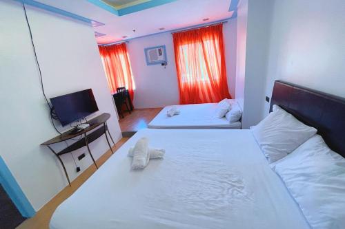 a hotel room with two beds and a television at Here Innstead Boracay in Boracay