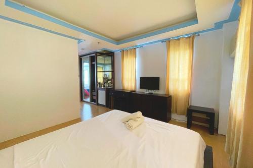 a bedroom with a white bed and a television at Here Innstead Boracay in Boracay
