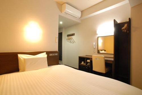 una camera con letto, scrivania e TV di AB Hotel Kakamigahara a Kakamigahara