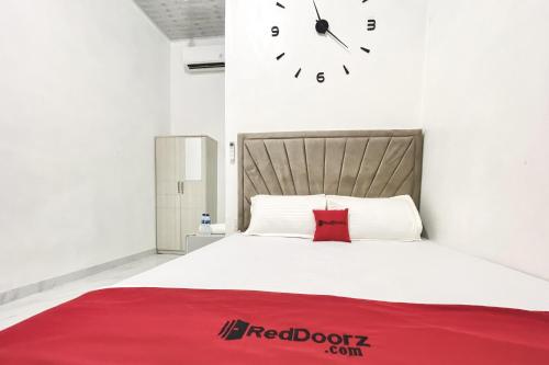 a bedroom with a bed with a clock on the wall at RedDoorz Syariah at Florensa Banda Aceh in Lamglumpang