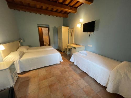 a hotel room with two beds and a television at Le Calvie, country house in Camerino