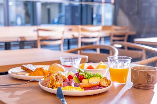 a plate of breakfast food on a table with orange juice at Tokyu Stay Kanazawa in Kanazawa
