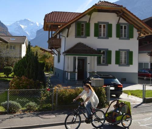 a woman riding a bike with a child in a carriage at Jungfrau Family Holiday Home in Matten