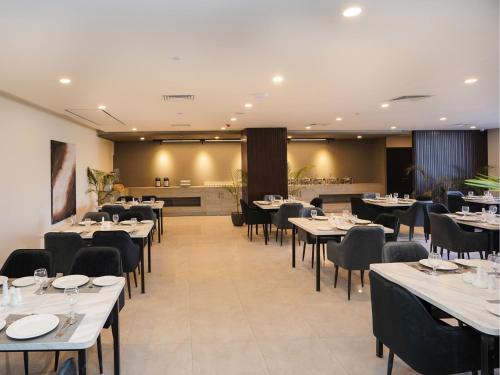 a dining room with white tables and black chairs at Hotel One Vogue Mall 35 Rawalpindi in Rawalpindi