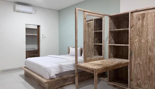 a bedroom with a bed and a wooden cabinet at Maisaba Living Sibang Gede in Bringkit