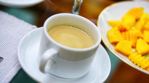 a cup of coffee on a plate next to some crackers at Sigiri SAAT Cabana in Sigiriya