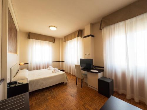 a hotel room with a bed and a desk with a computer at Hotel Astoria in Fidenza
