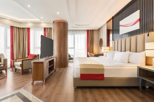 a hotel room with a bed and a television at Ramada by Wyndham Karapinar in Karapınar