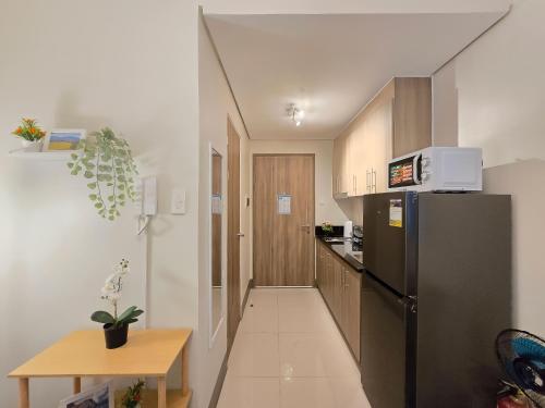 a kitchen with a black refrigerator and a table at 1BR Condotel with Balcony at FAME Residences #FM64 in Manila