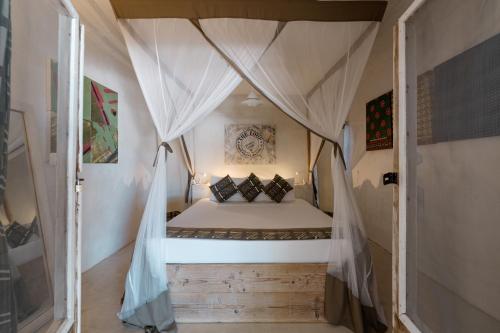 a small bedroom with a bed in a tent at The Loop Beach Resort in Jambiani