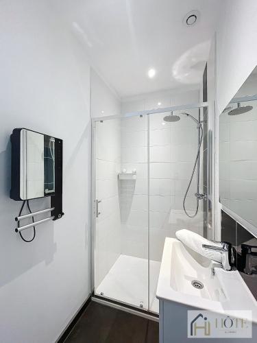 a bathroom with a shower and a sink and a tv at La Brise de Mer - Appt à 50m de la plage in Bray-Dunes