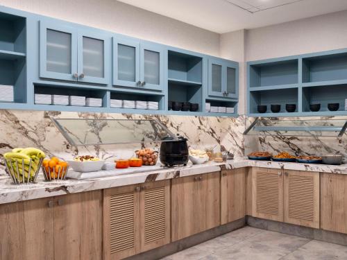 a kitchen with blue cabinets and fruits and vegetables on the counter at Hyatt Place Kansas City/Overland Park/Metcalf in Overland Park
