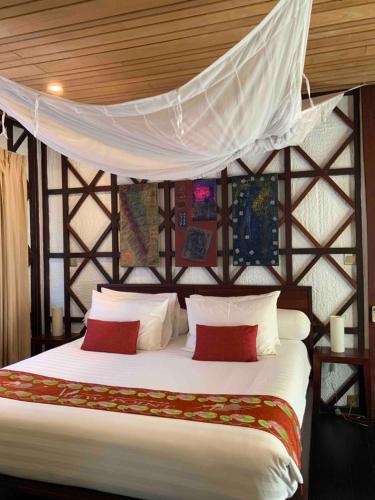 a bedroom with a bed with white sheets and red pillows at ViewPoint Ecolodge in Nyaung Shwe