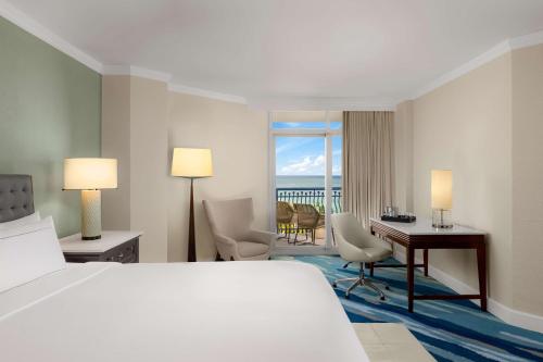 a hotel room with a bed and a desk with a view at Hilton Aruba Caribbean Resort & Casino in Palm-Eagle Beach