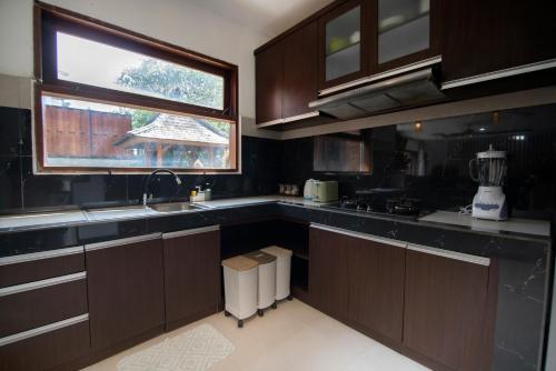a kitchen with brown cabinets and a window in it at Lamin Etan Saba Selatan in Keramas