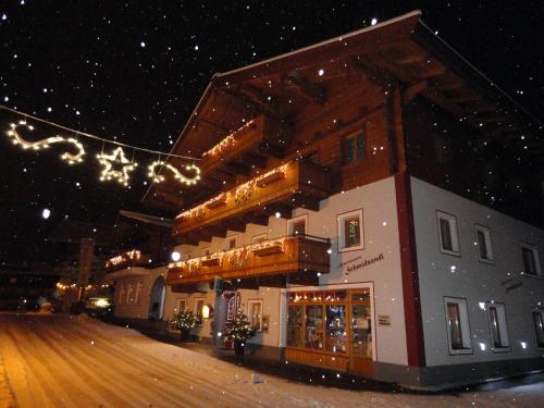 a building in the snow with christmas lights at Appartements Schmidsendl in Lofer