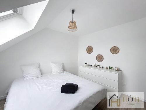 a bedroom with a white bed with a black bag on it at Le Cosy - 50m de la plage in Bray-Dunes