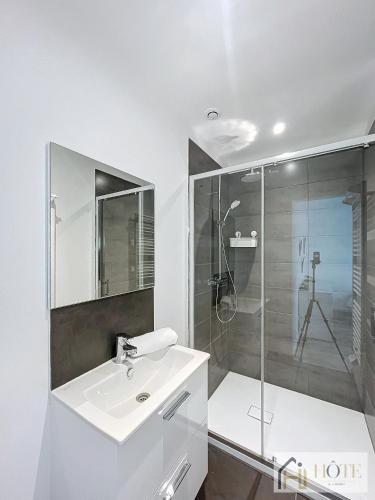 une salle de bain blanche avec un lavabo et une douche dans l'établissement Le Cosy - 50m de la plage, à Bray-Dunes