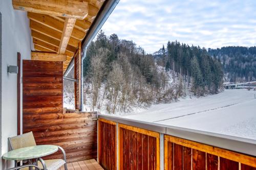 a balcony with a table and a view of the snow at COOEE alpin Hotel Kitzbüheler Alpen in Sankt Johann in Tirol