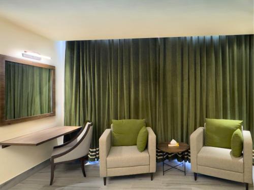 a room with two chairs and a desk and a table at Hotel One Vogue Mall 35 Rawalpindi in Rawalpindi