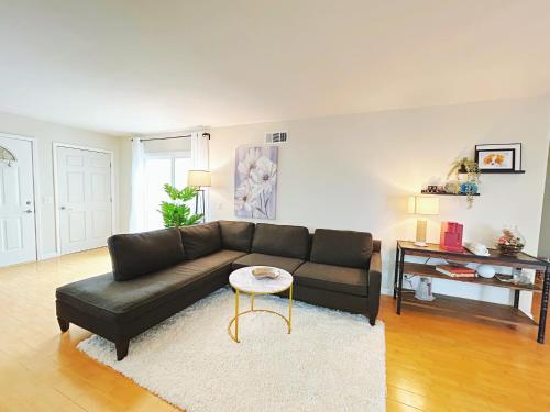 a living room with a black couch and a table at Brea Mall romantic two-bedroom house in Fullerton