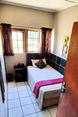 a bedroom with a bed and a window at The Airport Lodge - East London in East London