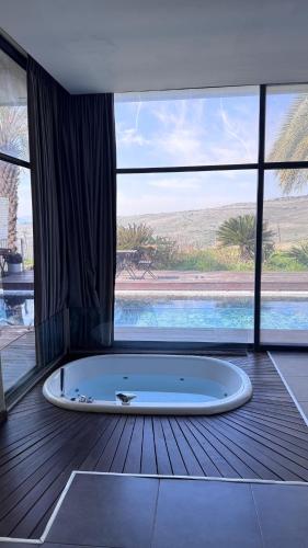 a large bath tub in a room with a pool at Diamond Mansion-Suite A in Had Nes