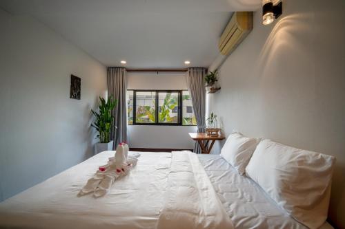 a bedroom with a white bed with a stuffed animal on it at Pomelo Outpost Cambodia ដំណាក់ភ្នំក្រោម in Phumĭ Rœssei Lŭk