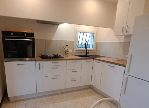 une cuisine avec des armoires blanches et un appareil noir dans l'établissement Grand appartement, 2 chambres et jardin, à Nîmes