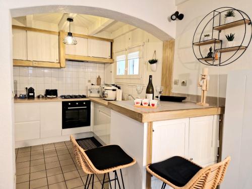 une cuisine avec des armoires blanches et un comptoir avec des tabourets dans l'établissement Maison Richelieu, à Bram