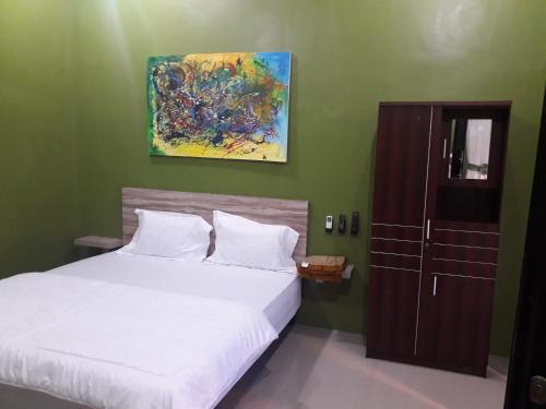 a bedroom with a bed and a painting on the wall at Ahza syariah in Rantauprapat