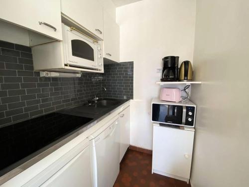 une petite cuisine avec un évier et un micro-ondes dans l'établissement Résidence Diamant 1 - Joli studio au plein cœur de la station des Deux Alpes avec balcon plein SUD MAE-9571, à Vénosc