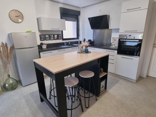 une cuisine avec un îlot et deux tabourets de bar dans l'établissement Chez Steph et Guillaume, à Châtenois