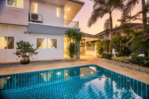 a swimming pool in front of a house at Grande Pool Villa BBQ&Pool party in Bang Sare